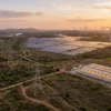 Aerial view of India energy infrastructure with transmission towers, solar farm, wind turbines and an EV charging hub
