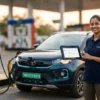 CPO reviewing GST on EV charging billing dashboard beside an EV with a green number plate at a fuel forecourt charging station