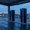 EV charger connectivity cabinet with cellular antenna beside DC fast chargers — M2M SIM card link to the charging backend