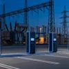 OpenADR 3.0 grid-facing interface for charge point operators: DC fast chargers beside a high-voltage substation at dusk