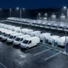 Smart charging for fleet depots: electric delivery vans queued in a depot yard at night with only some connected to shared DC chargers
