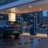 Digital advertising totem beside DC fast chargers on a forecourt, illustrating EV charging station advertising inventory